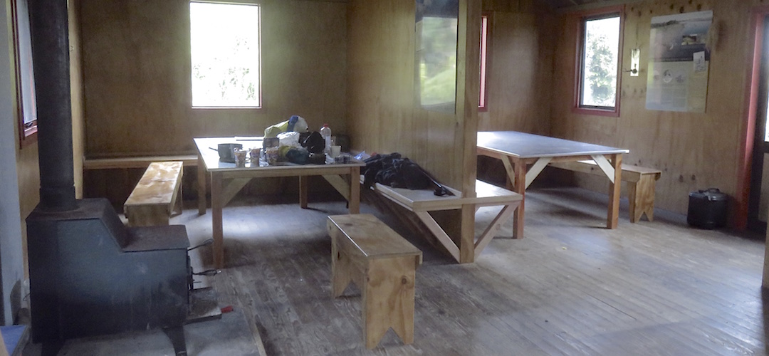 Two big tables in separate areas in the living room.  | Martins Bay Hut, Hollyford Track