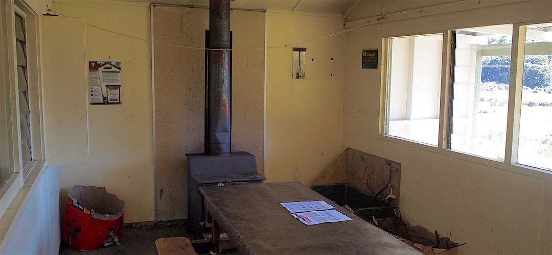 The living area has a standard large firebox. | Trilobite Hut, Kahurangi National Park