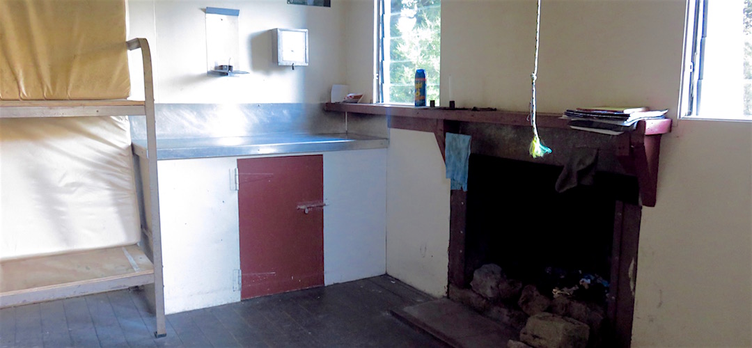 The open fire and some bench space. | Larrikin Creek Hut, Kahurangi National Park