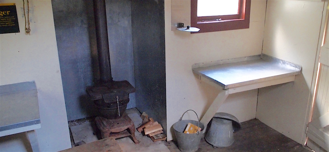 The original open fire has been replaced by a pot belly stove. | McConchies Hut, Matiri River, Kahurangi National Park