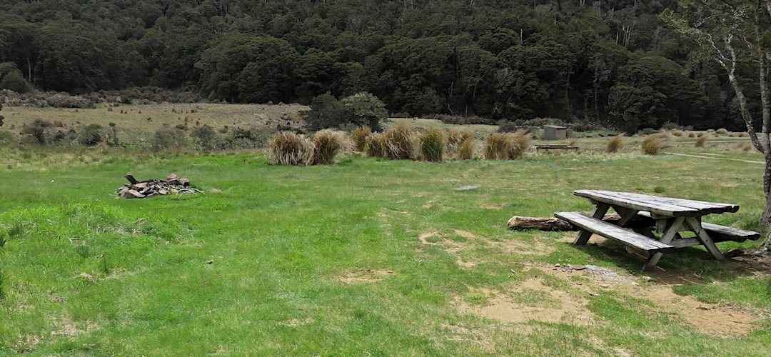 One of the campsites has a picnic table and fireplace. | Cobb River campsite, Kahurangi National Park