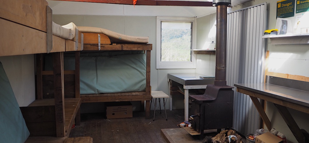 Typical NZFS SF70 interior, with a woodburner. | Mudflats Hut, Arahura River, West Coast