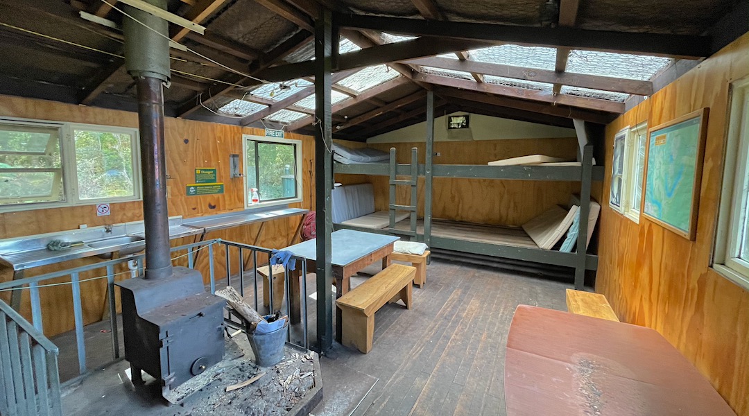 Wood burner and sleeping platforms. | Monowai Hut