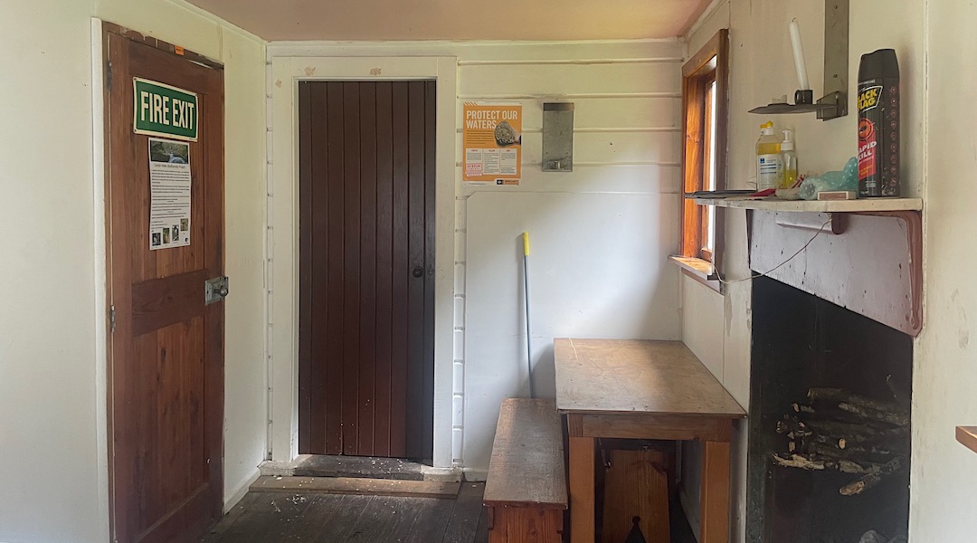 The linking room with the bench and open fire. | Carlyle Hut, Lake Sumner Forest Park