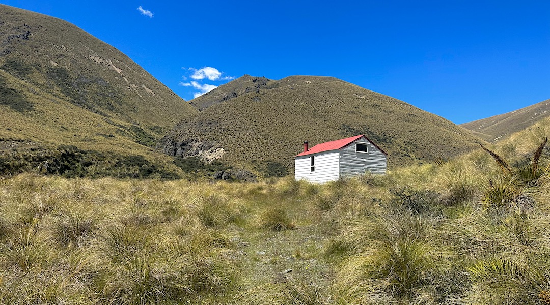 The hut is nestled into the hills at the top of the valley. | Otamatapaio Hut, Oteake Conservation Park