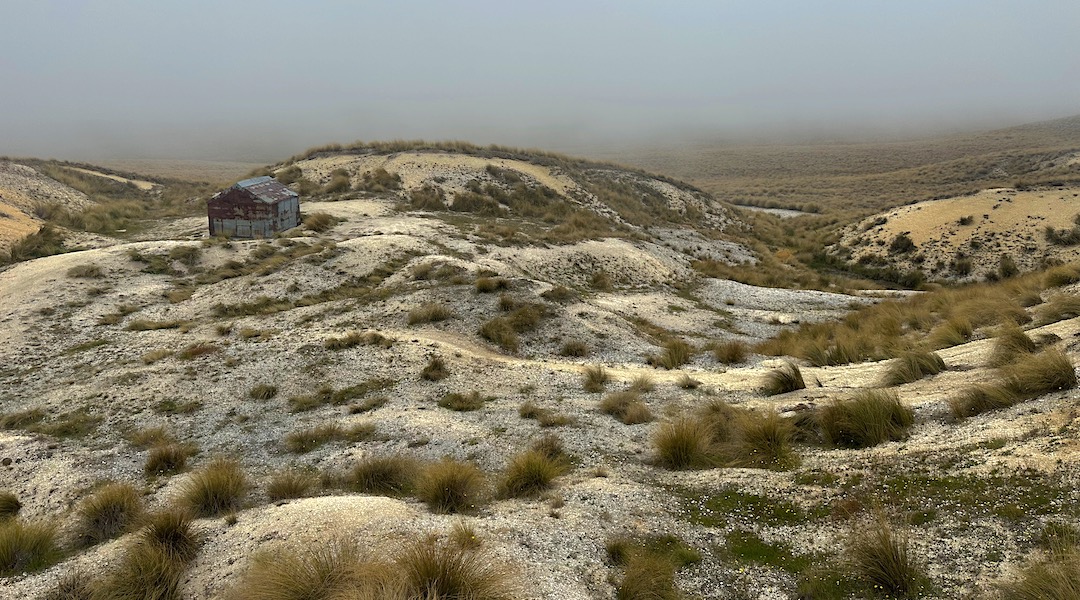 The hut is surround by mining spoil. | Brown Hut, Oteake Conservation Park