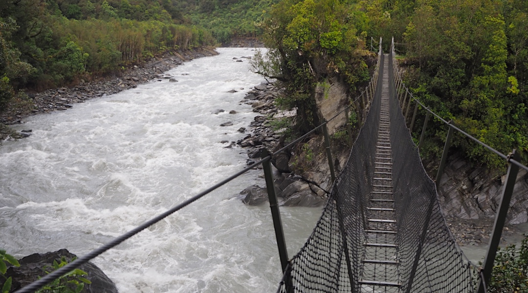 West Coast rivers are steep, swift, and bouldery, hence difficult to cross. | Swingbridge, Arahura River