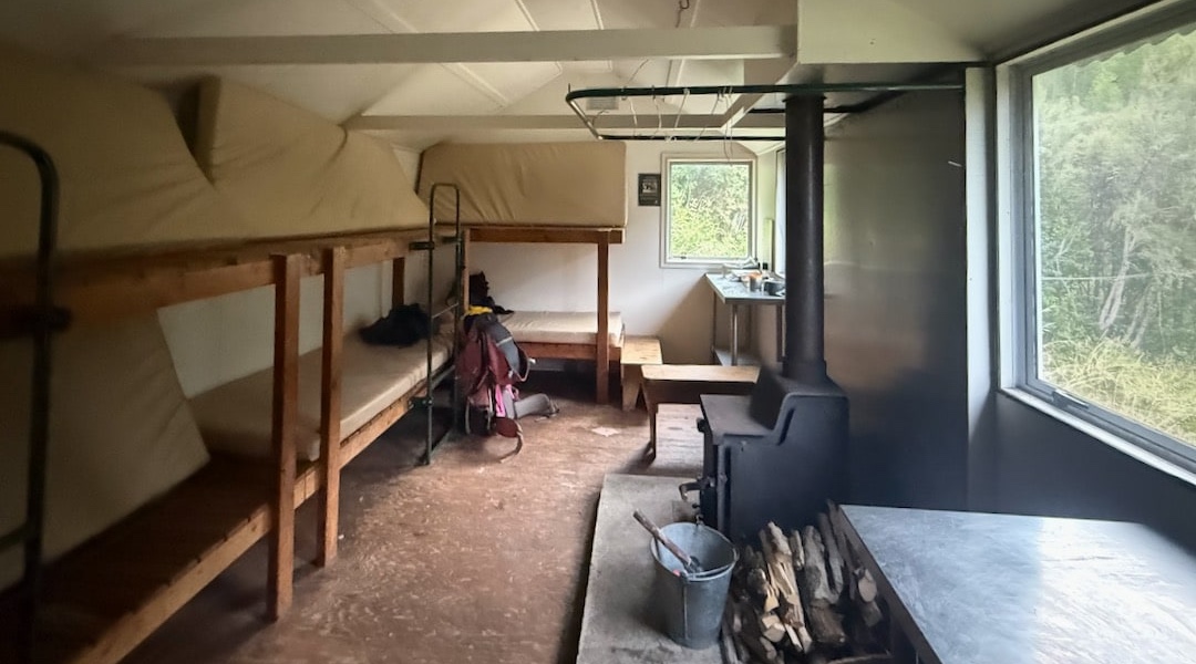 The interior has been renovated with a woodburner, new windows and bunks, and stainless benches. | Hapuku Hut, Ka Whata Tu o Rakihouia Clarence