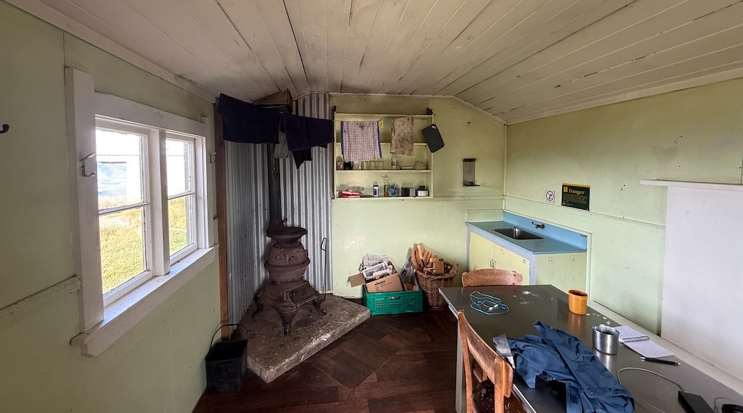 A messy living room with the woodburner. Bring your own firewood. | Mt Bee Bunkrooms, Eyre Mountains/Taka Rā Haka Conservation Park