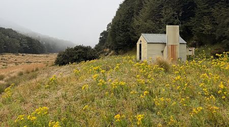 Hut is on an old river terrace, above the swampy tussock. | Cromel Branch Hut, Eyre Mountains/Taka Rā Haka Conservation Park